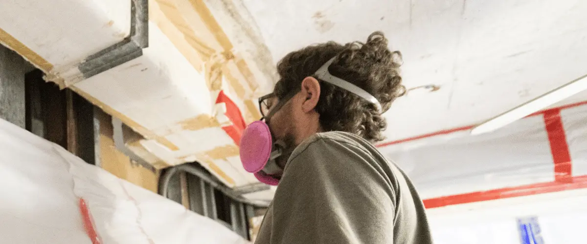 Certified mold remediation specialist inspecting a water-damaged wall